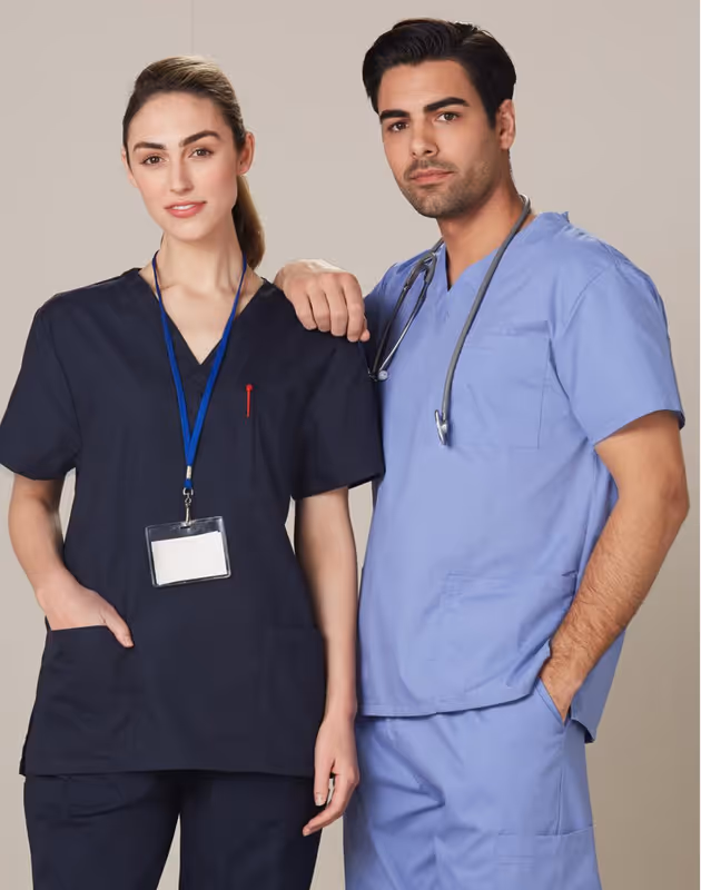 Woman and man wearing medical scrubs, the man has a stethoscope around his neck, posing together against a neutral background.