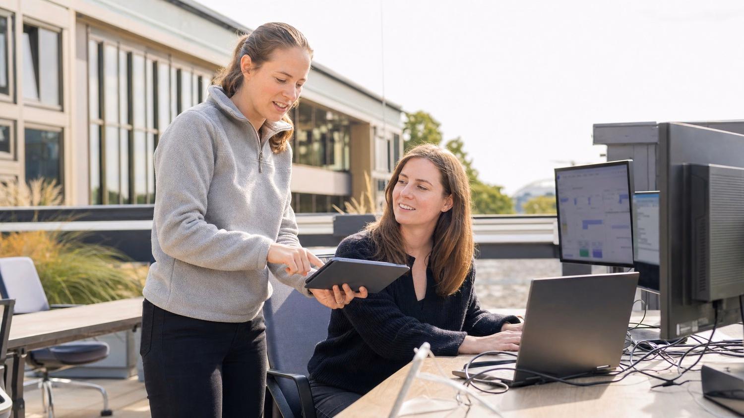 Woman gestures at tablet on sunny office terrace
