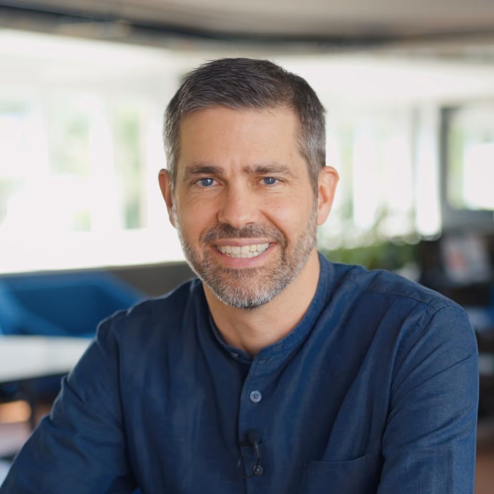 A middle-aged man with short brown hair and a dark blue shirt smiling toward the camera.