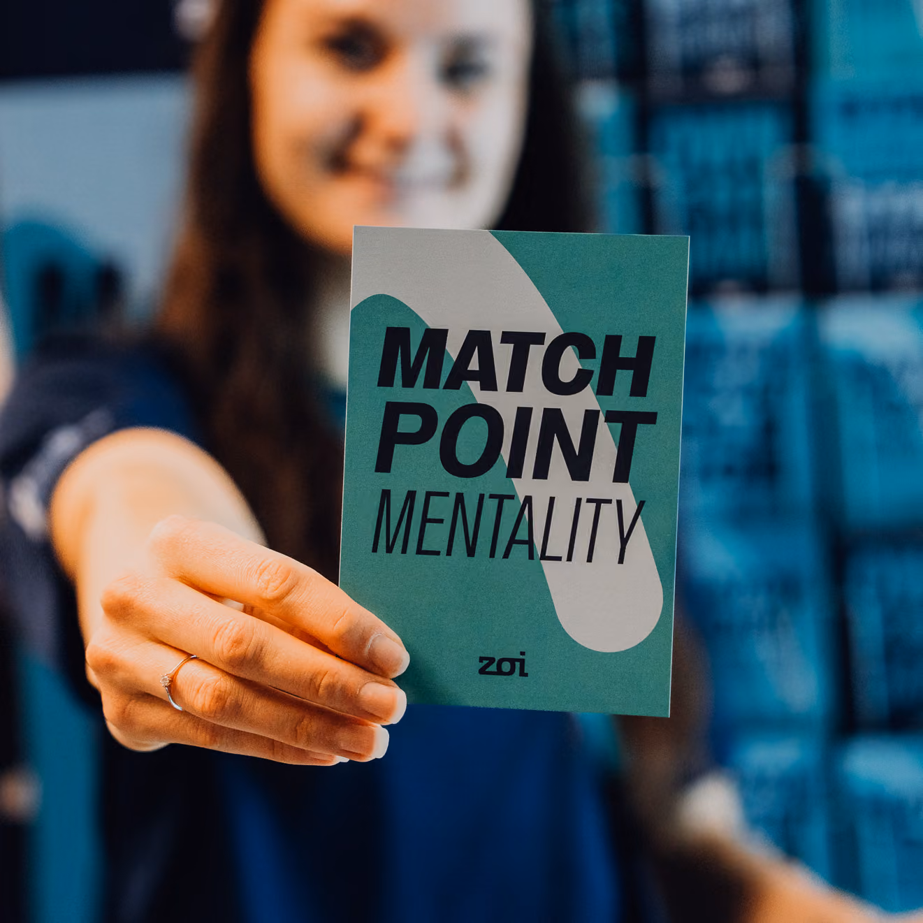Person holding a card that says MATCH POINT MENTALITY with a green and white design.