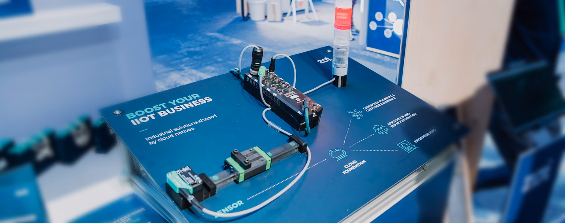 Einrichtung eines industriellen IoT-Sensors auf einer blauen Oberfläche mit Text zur Förderung des IIoT-Geschäfts und zur Cloud-Grundlage.