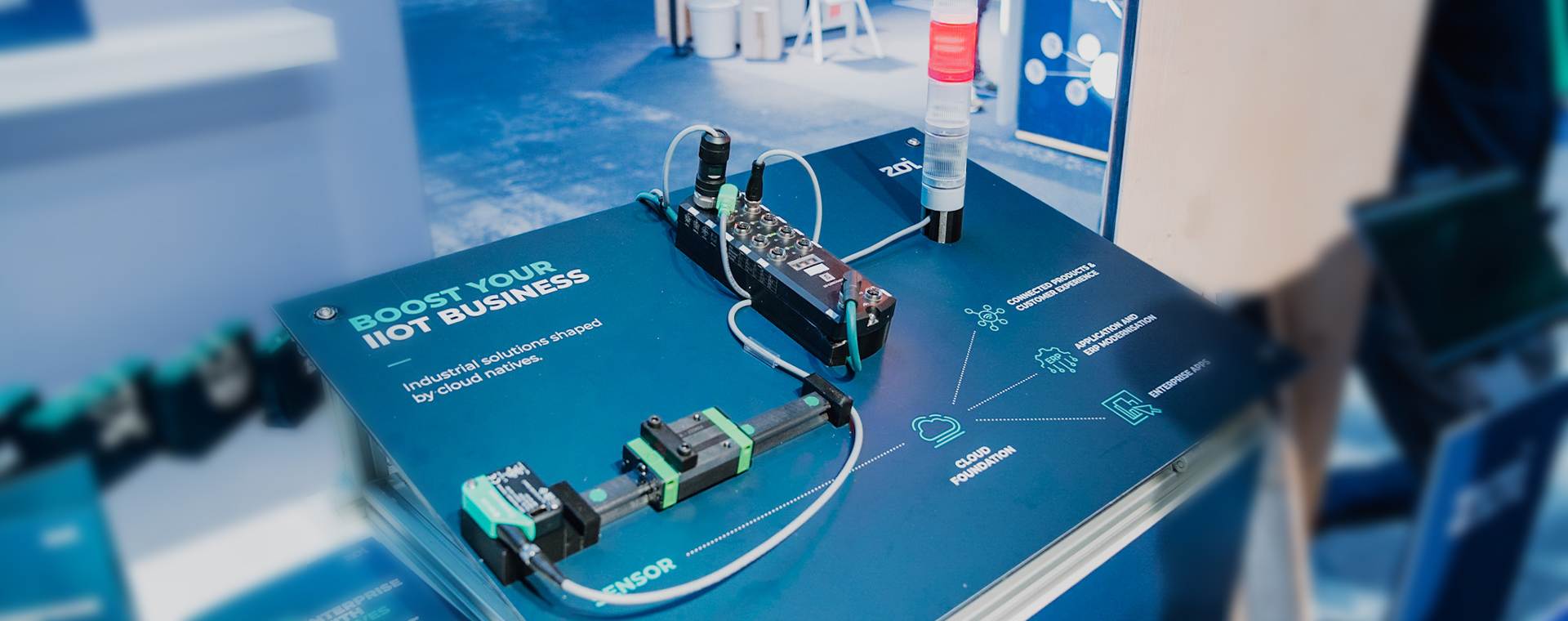 Einrichtung eines industriellen IoT-Sensors auf einer blauen Oberfläche mit Text zur Förderung des IIoT-Geschäfts und zur Cloud-Grundlage.