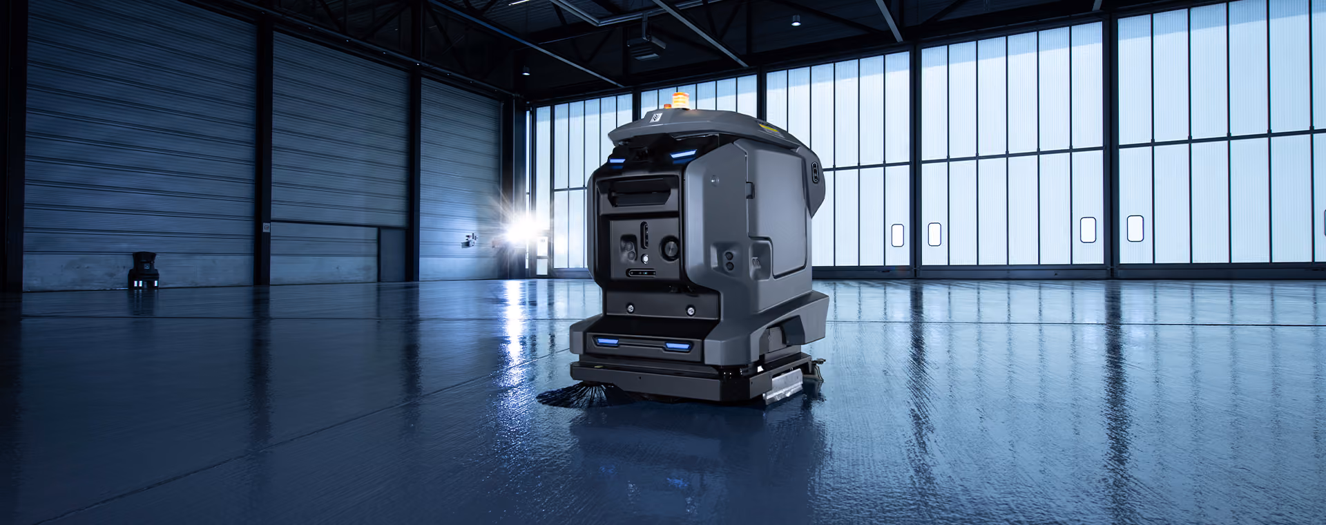 Un moderno robot de limpieza de suelos autónomo que opera dentro de un espacioso almacén industrial.