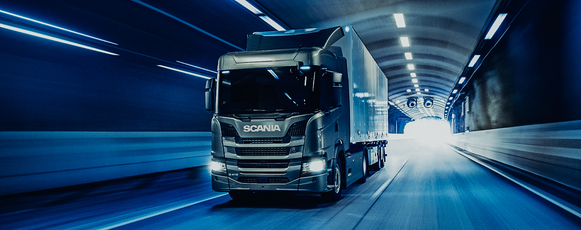 Scania G410 Truck fährt durch einen hell erleuchteten Tunnel.