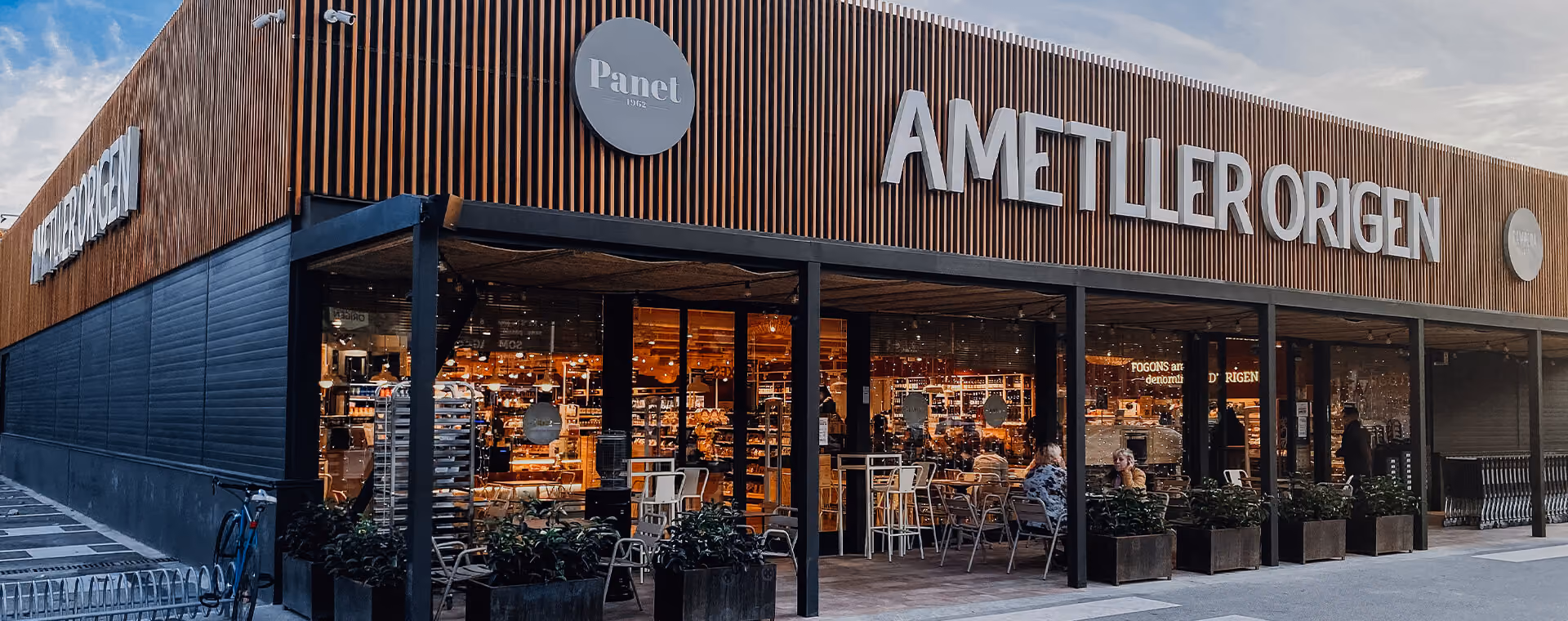 Exterior of Ametller Origen store with wood paneling and outdoor seating under a covered porch.