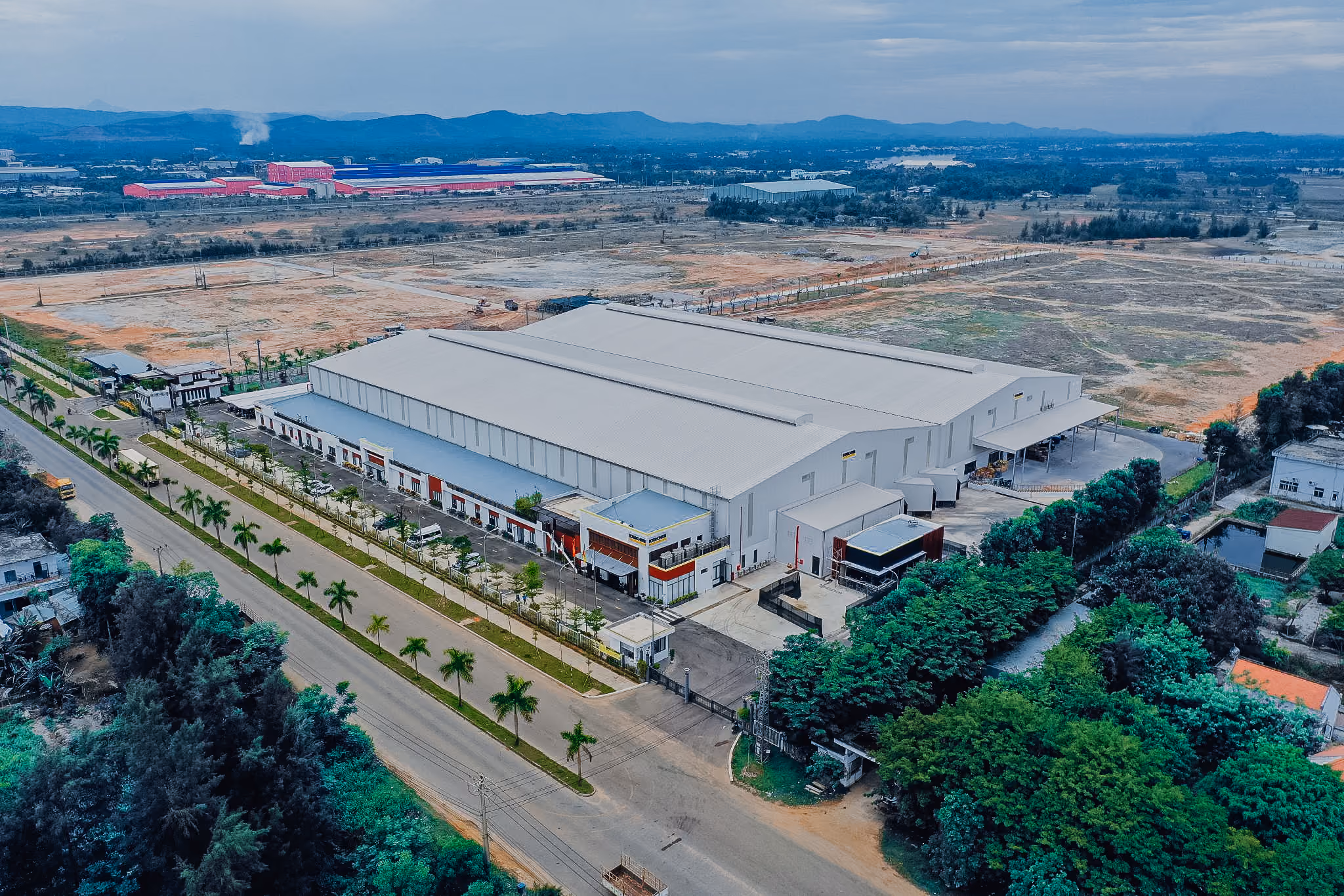 Aerial view of a large Kärcher industrial warehouse and production facility, surrounded by roads, greenery, and fields.