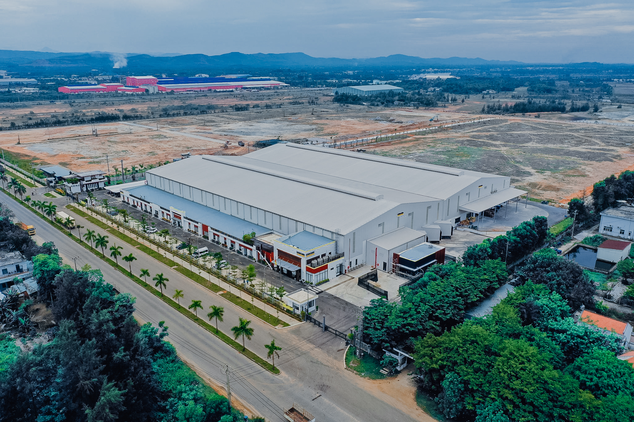 Vista aérea de un gran almacén industrial e instalación de producción de Kärcher, rodeado de carreteras, zonas verdes y campos.