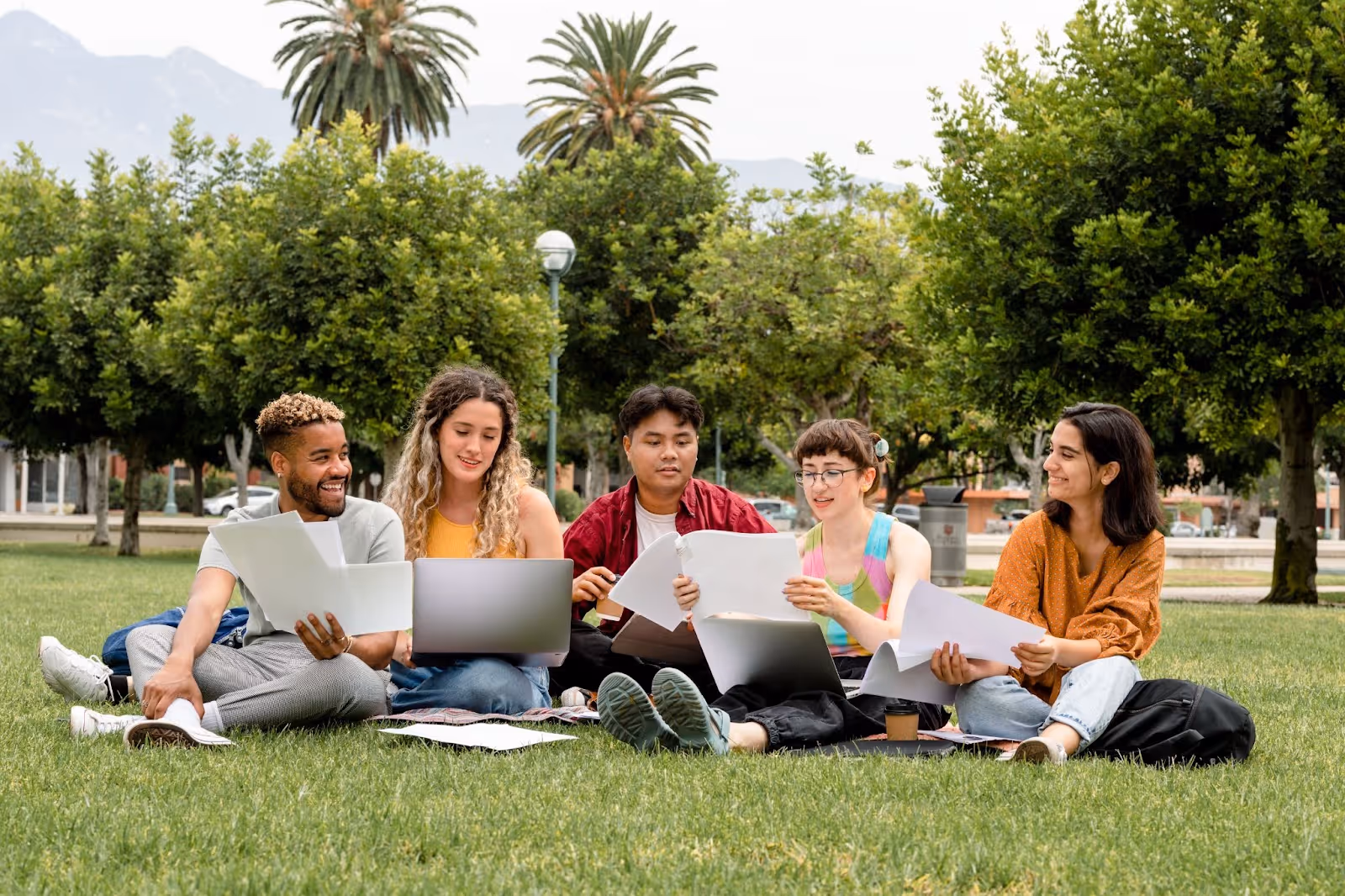Groupe de 5 étudiants en train de réviser dans un parc