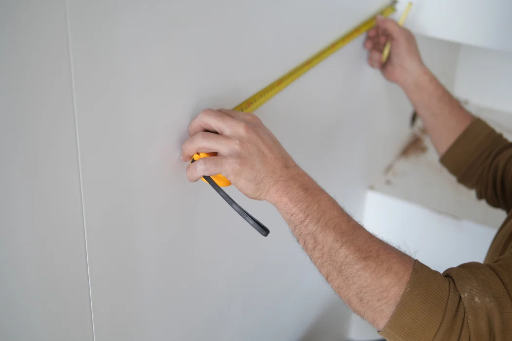 Mesure d'un mur avec un mètre ruban pour vérifier une erreur de surface habitable sur la taxe foncière