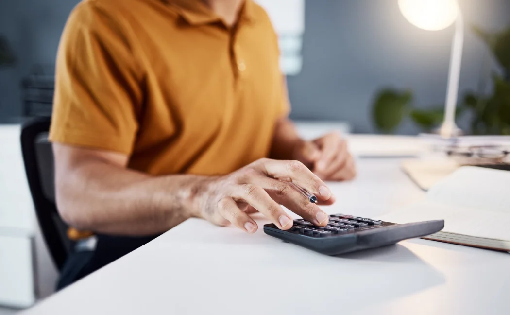 Homme tapant sur sa calculatrice pour comparer les charges de copropriété et trouver le syndic le moins cher