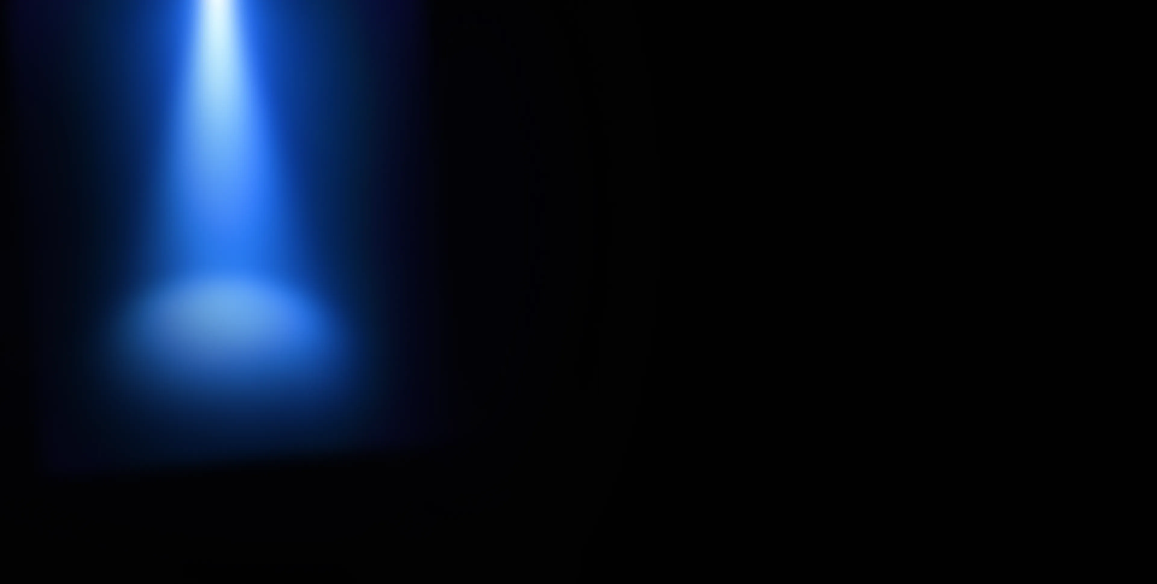 A blue spotlight shining downward into darkness, illuminating a circular area.