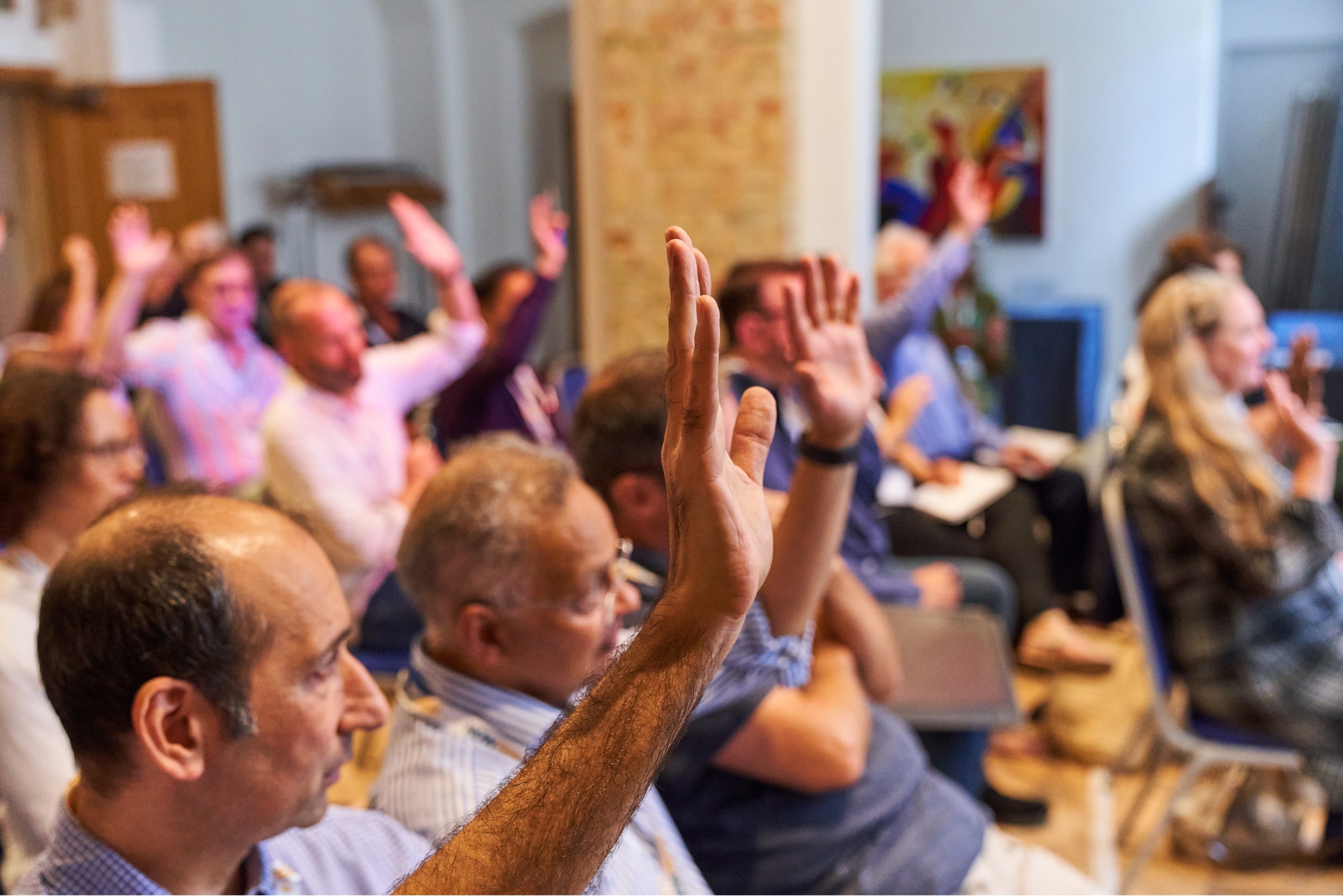 Secondary school pupils with hands raised eagerly in a classroom lesson.