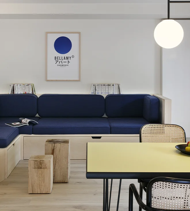 Intérieur d'un appartement Bellamy avec une table et un espace salon composé d'un canapé bleu et d'une décoration mêlant inspiration japonaise et design scandinave