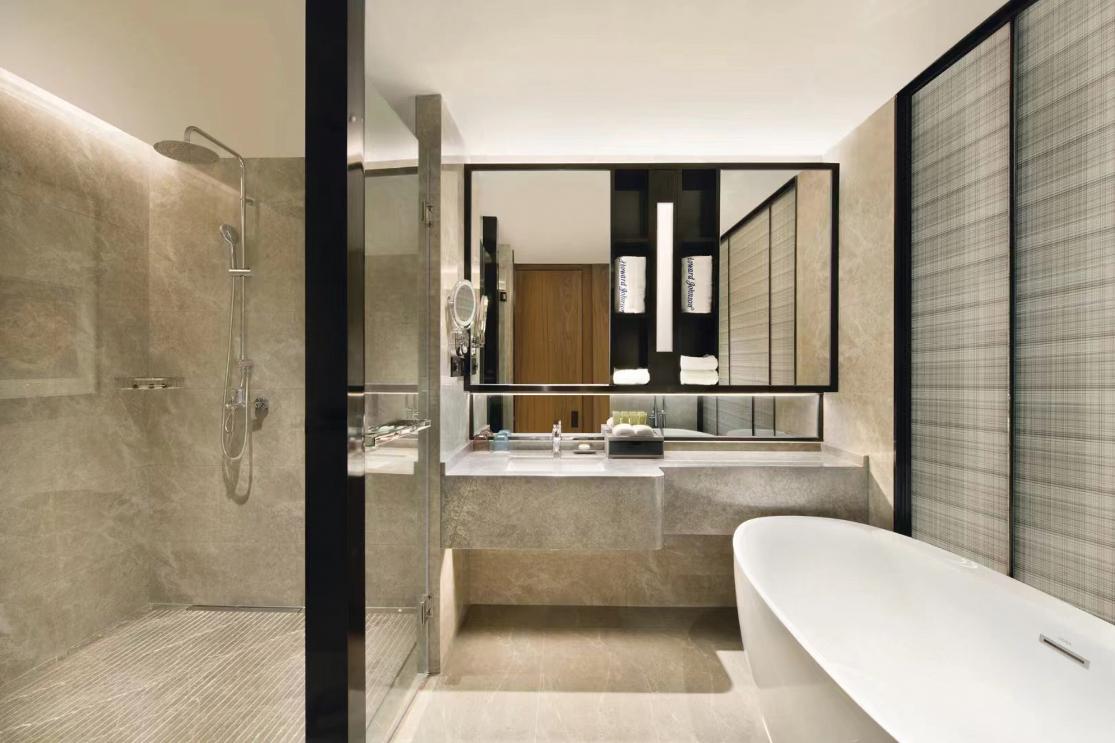 Contemporary hotel bathroom featuring a walk in shower, stone vanity unit, and freestanding bathtub.