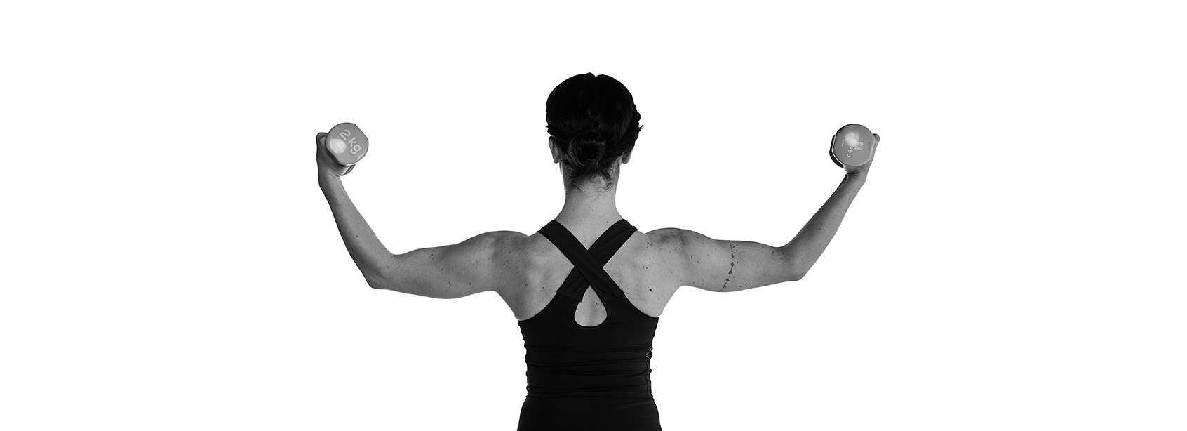 Espalda de mujer, posición de pilates con mancuernas
