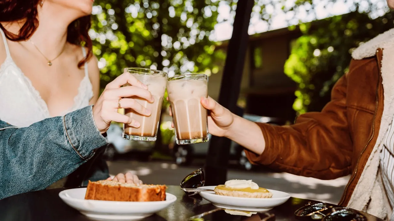 A man and woman sitting at a table enjoying a meal with plates of food and a glass of lemon water.
