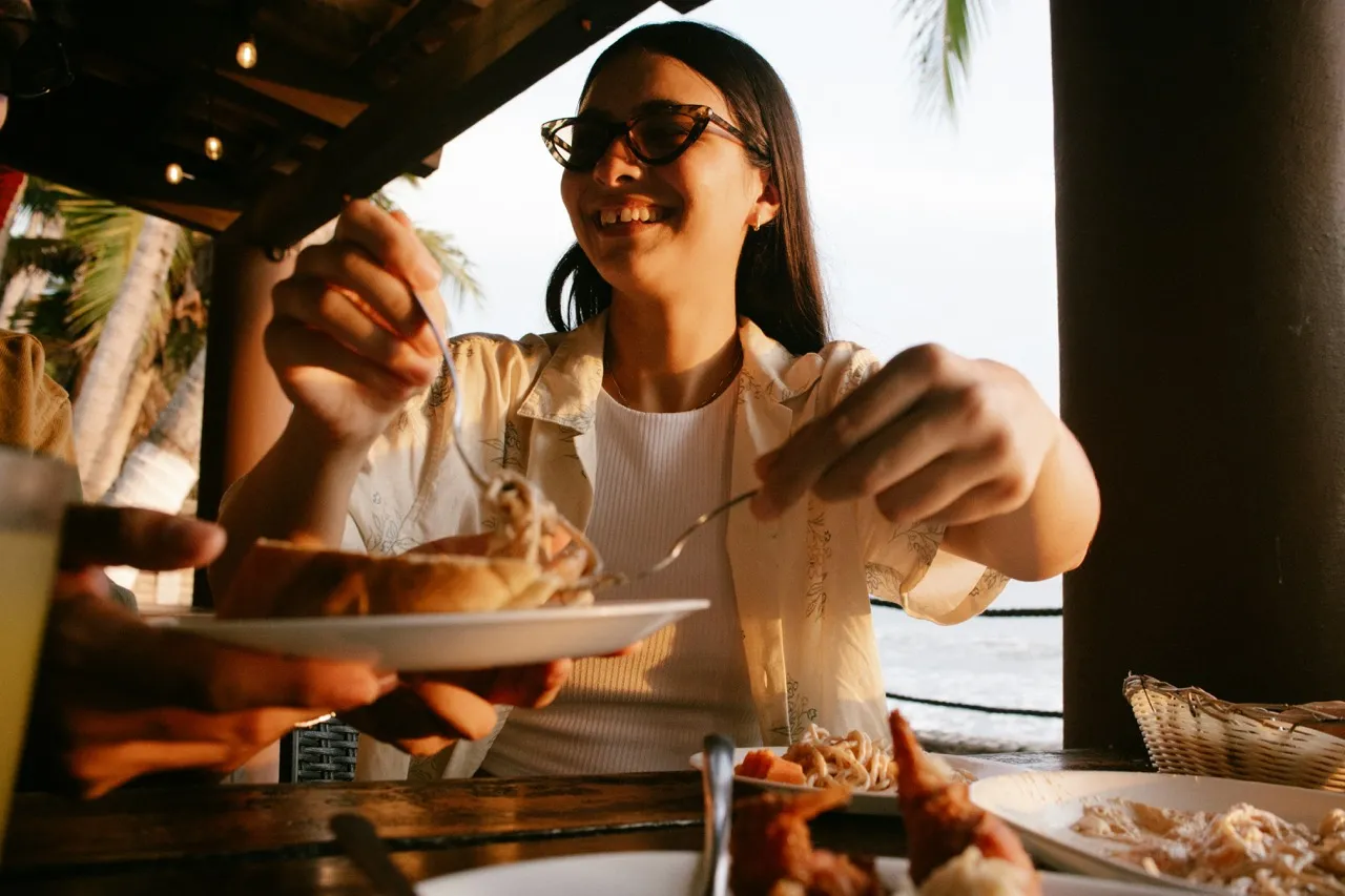 A man and woman sitting at a table enjoying a meal with plates of food and a glass of lemon water.