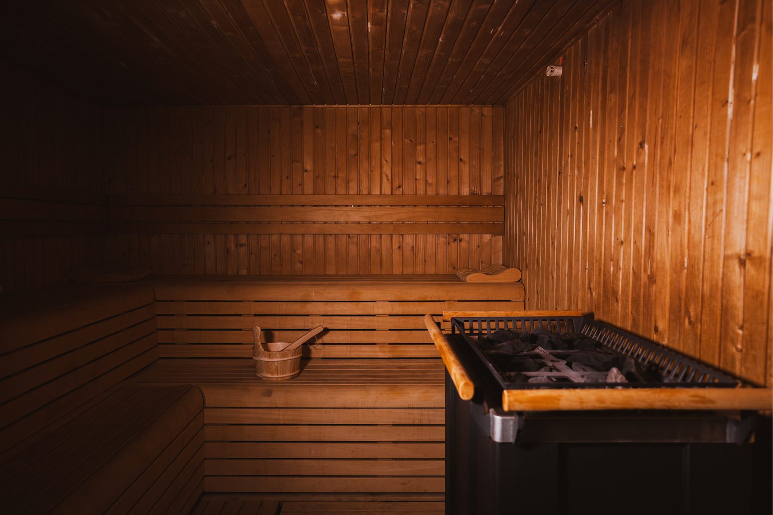 Intérieur d'un sauna en bois avec un seau en bois et une cuillère sur la banquette.