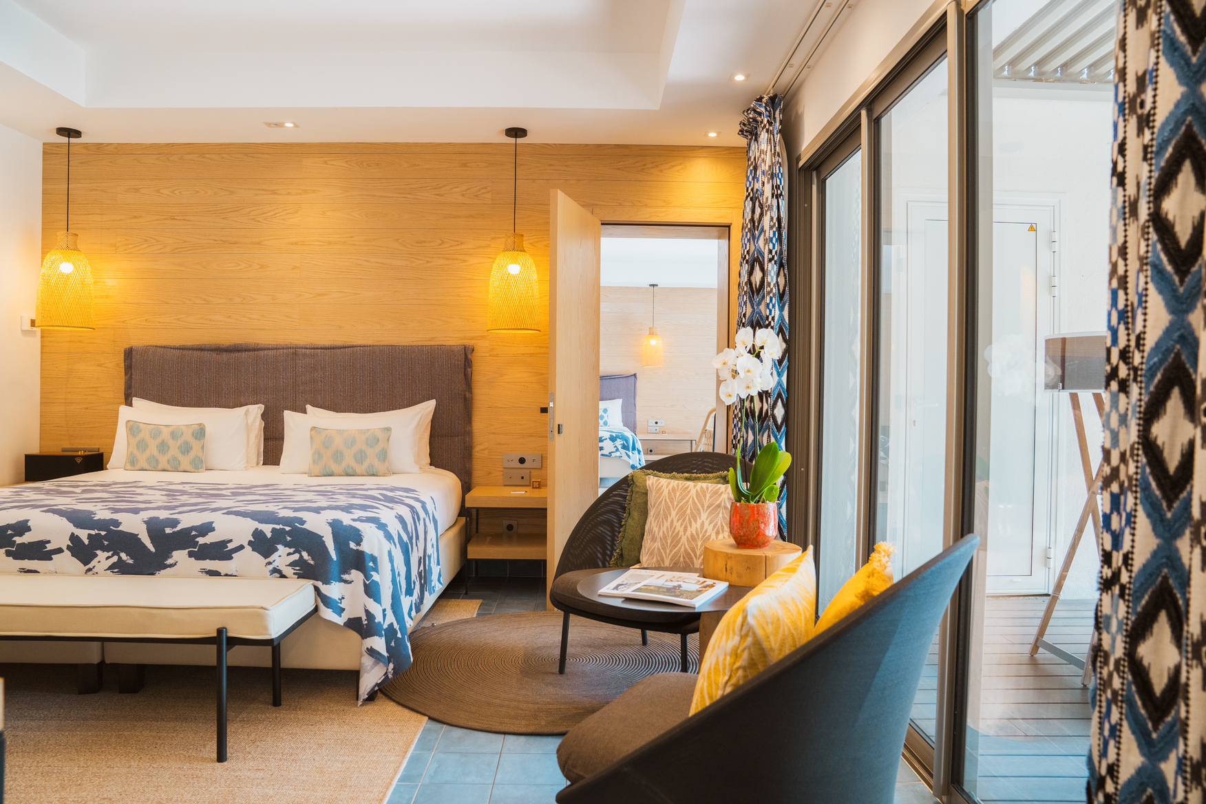 hambre Ibiza chic avec éclairage d'ambiance chaleureux, jeté de lit bleu et blanc et ouverture directe sur un patio privé.