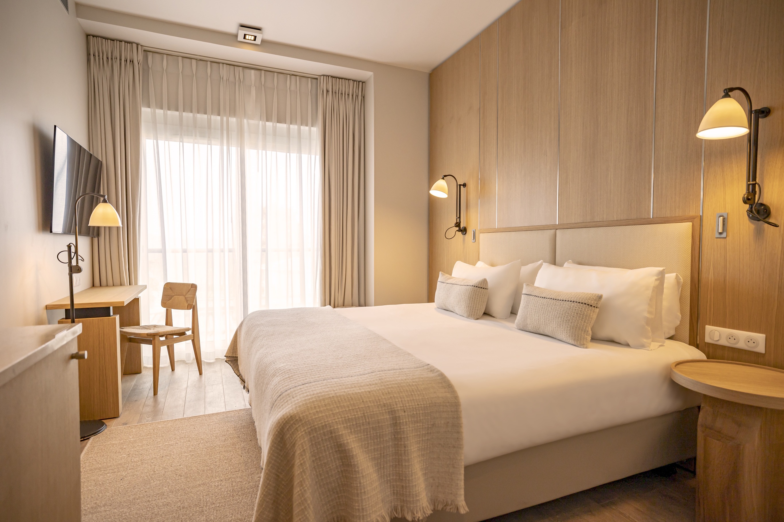 uite lumineuse style naturel avec accès balcon, rideaux en lin beige et parquet massif créant une atmosphère apaisante.