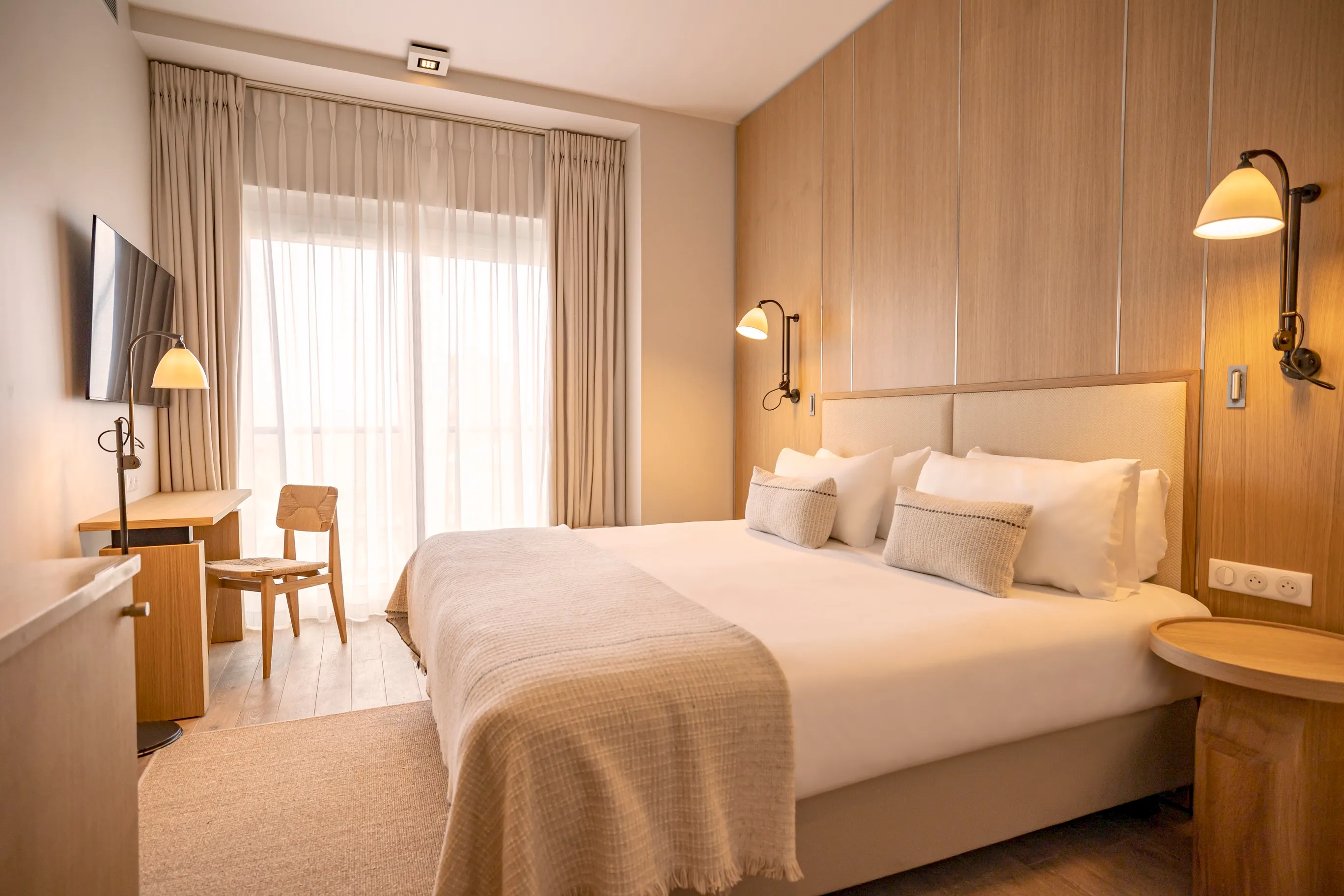 uite lumineuse style naturel avec accès balcon, rideaux en lin beige et parquet massif créant une atmosphère apaisante.