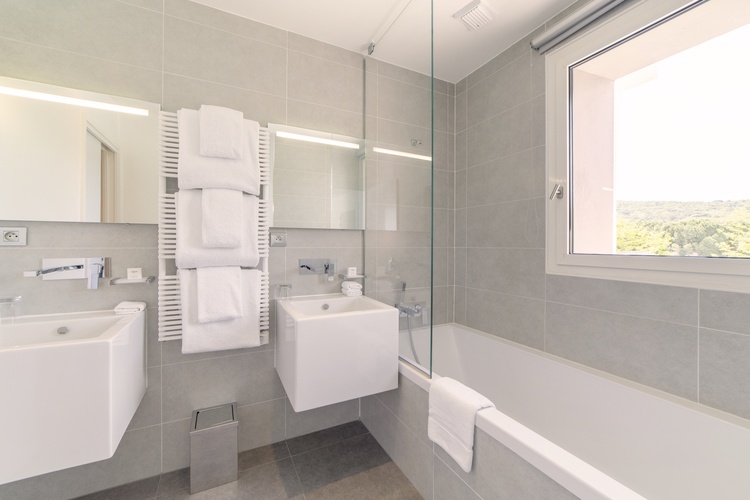 Salle de bain moderne et claire avec double vasque suspendue, baignoire blanche et murs gris perle pour un style naturel chic.