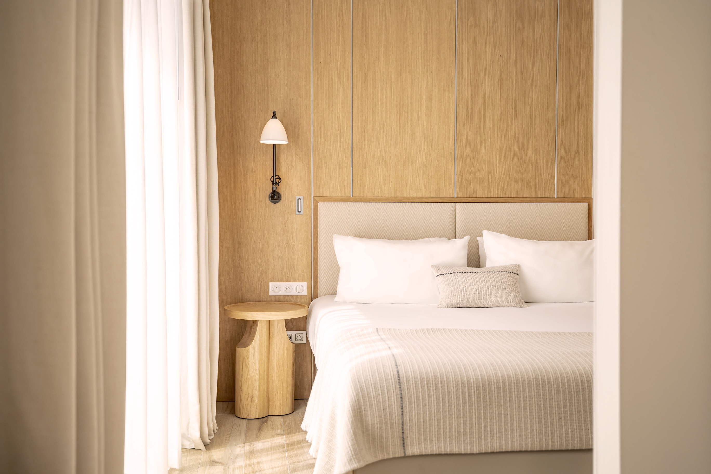 Mobilier artisanal de luxe en bois massif et finitions soignées dans une chambre d'hôtel de standing.