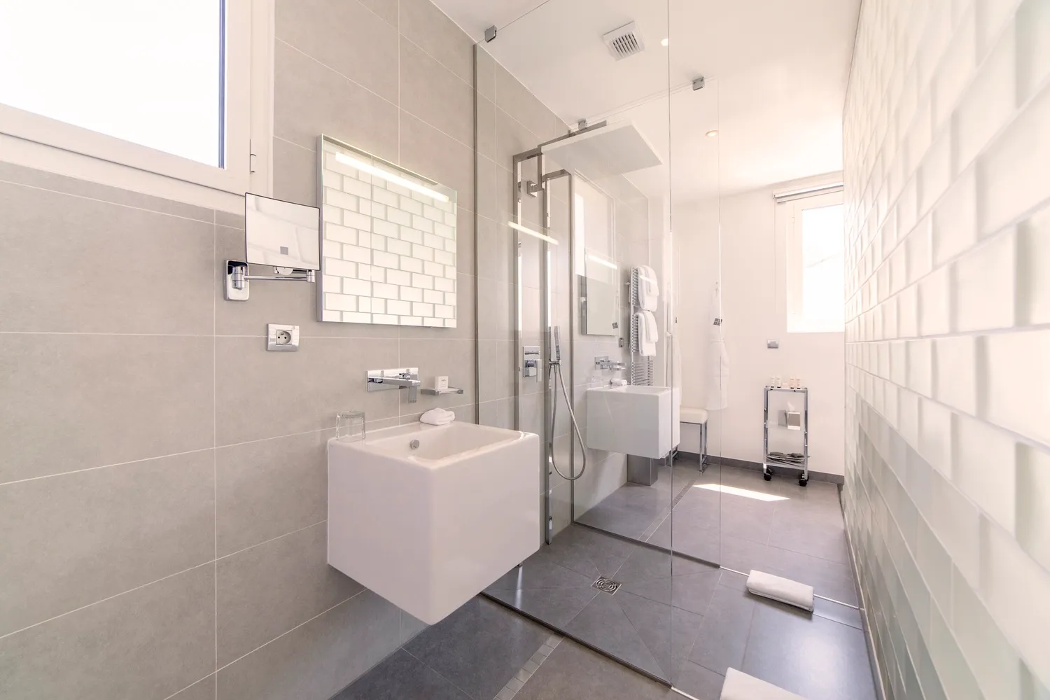 Salle de bain de prestige avec douche à l'italienne, vasque design suspendue et carrelage mural texturé blanc.