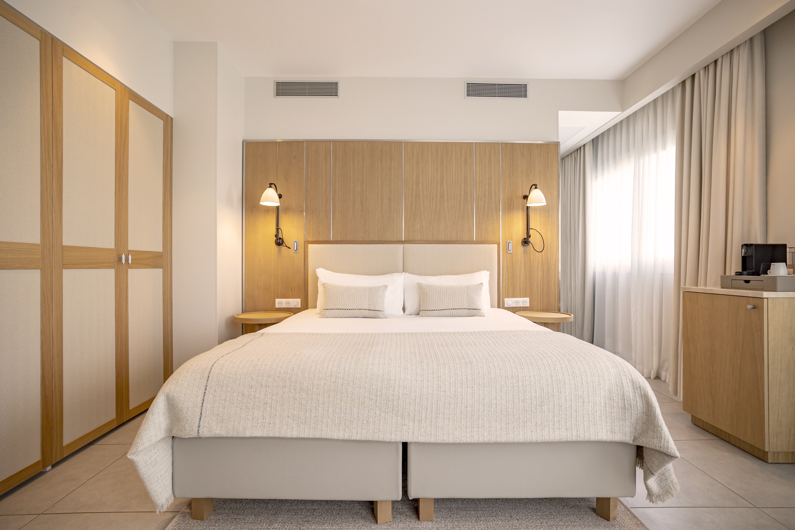 Grande chambre Prestige avec dressings intégrés en bois clair, climatisation discrète et décoration épurée haut de gamme.