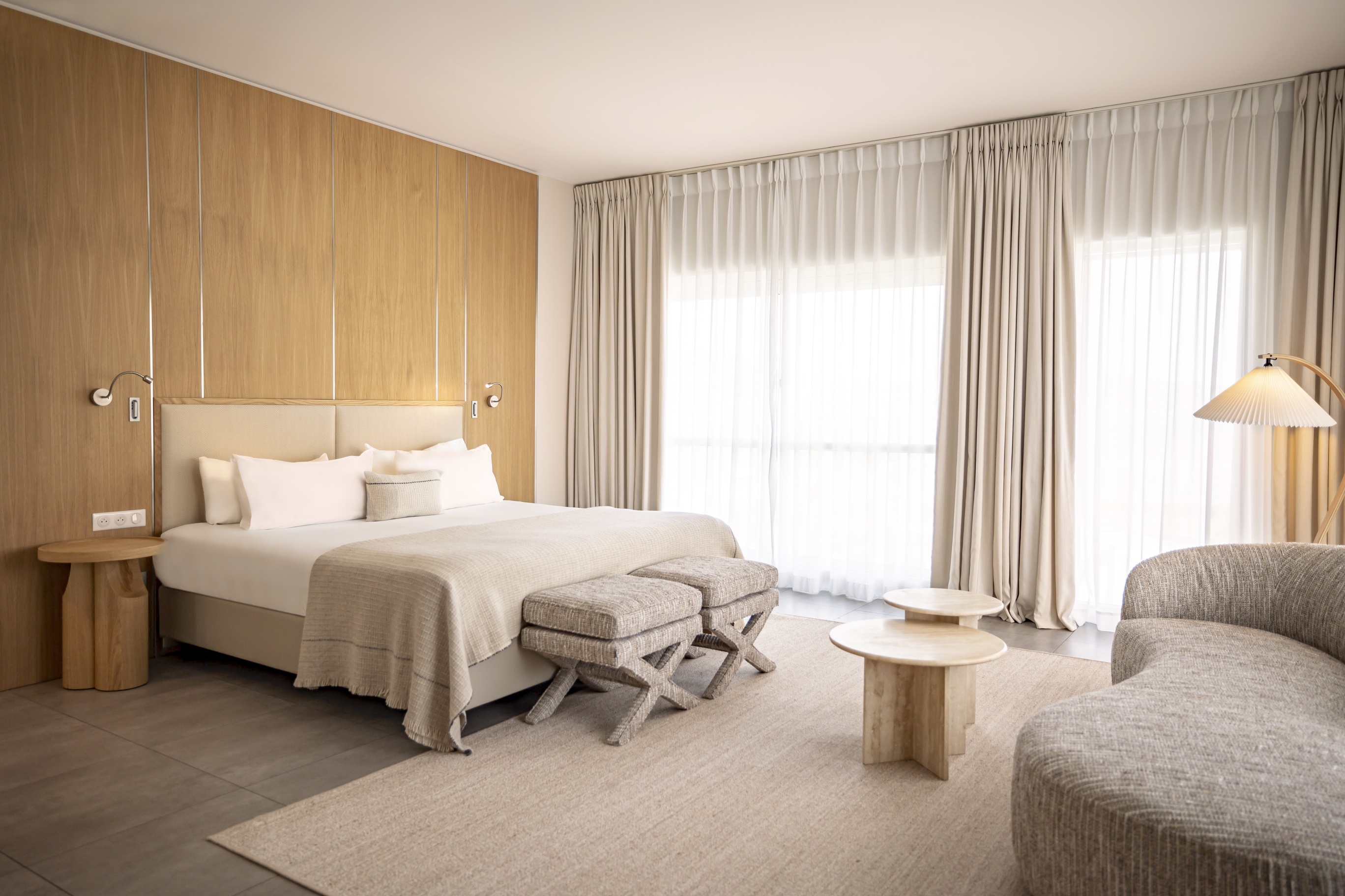 Espace détente de la Suite Junior avec canapé incurvé aux lignes organiques, tables basses en bois et luminaire design