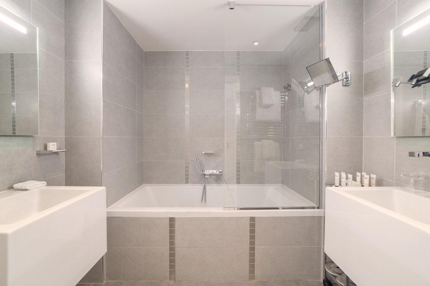 Salle de bain design avec baignoire, double vasque épurée et parois vitrées 