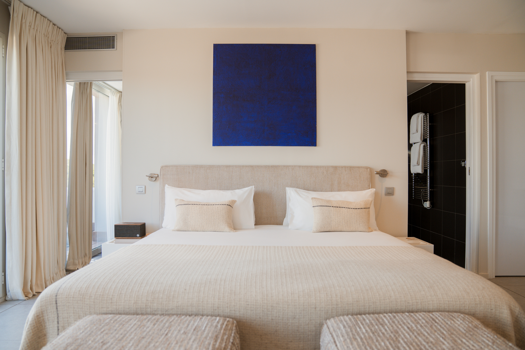 Chambre de prestige au style Natural Sea avec tableau d'art bleu cobalt, lit king-size et ambiance lumineuse épurée.