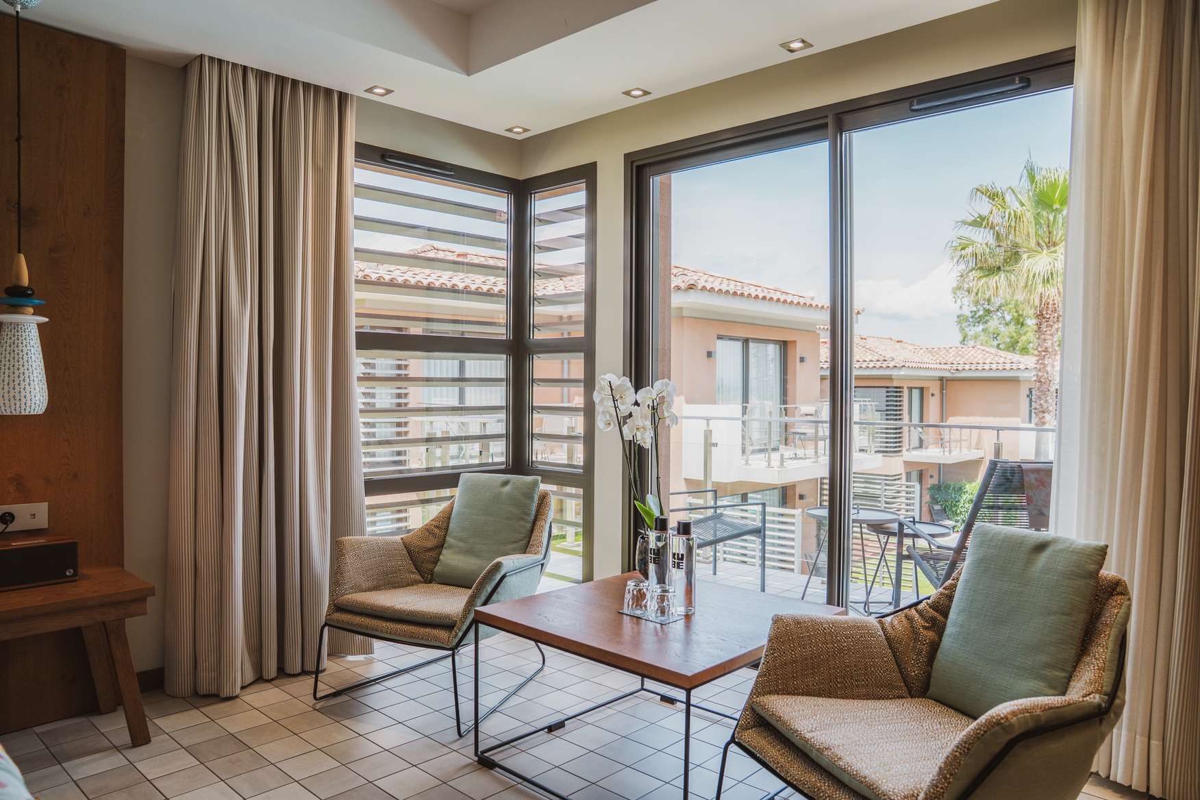 Coin salon de chambre Deluxe avec fauteuils design, grandes fenêtres panoramiques et vue imprenable sur la mer.