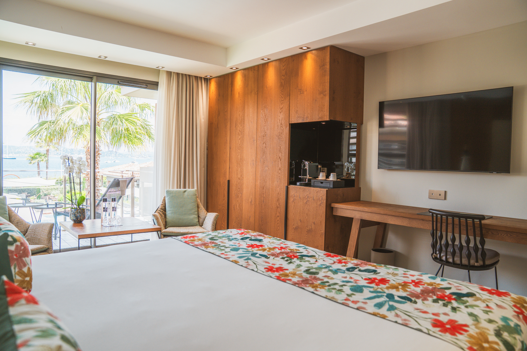 Chambre de luxe lumineuse avec placards intégrés en bois noble et accès direct vers une terrasse privée ensoleillée