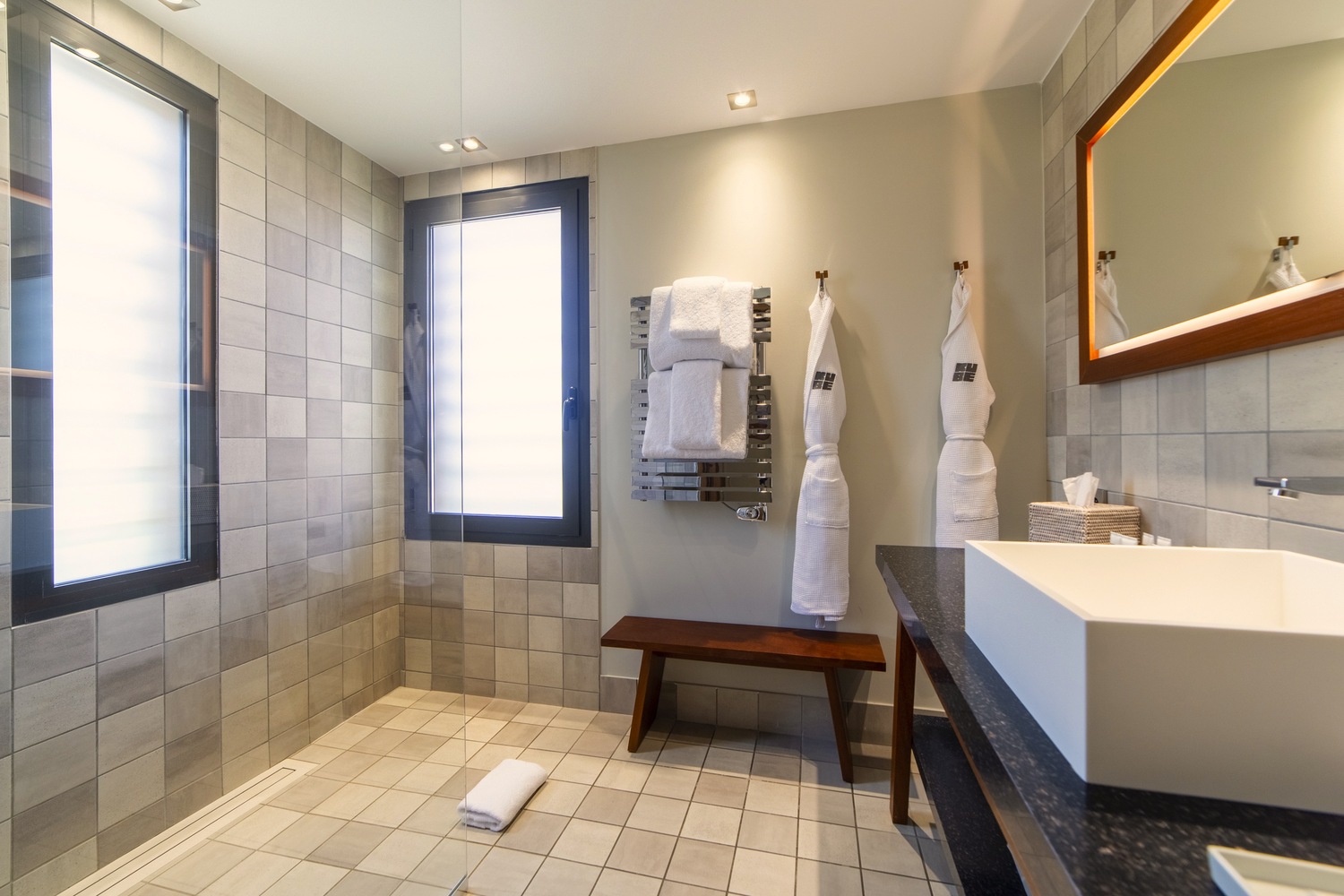Salle de bain de standing avec vasque rectangulaire, grand miroir design et finitions en matériaux naturels.