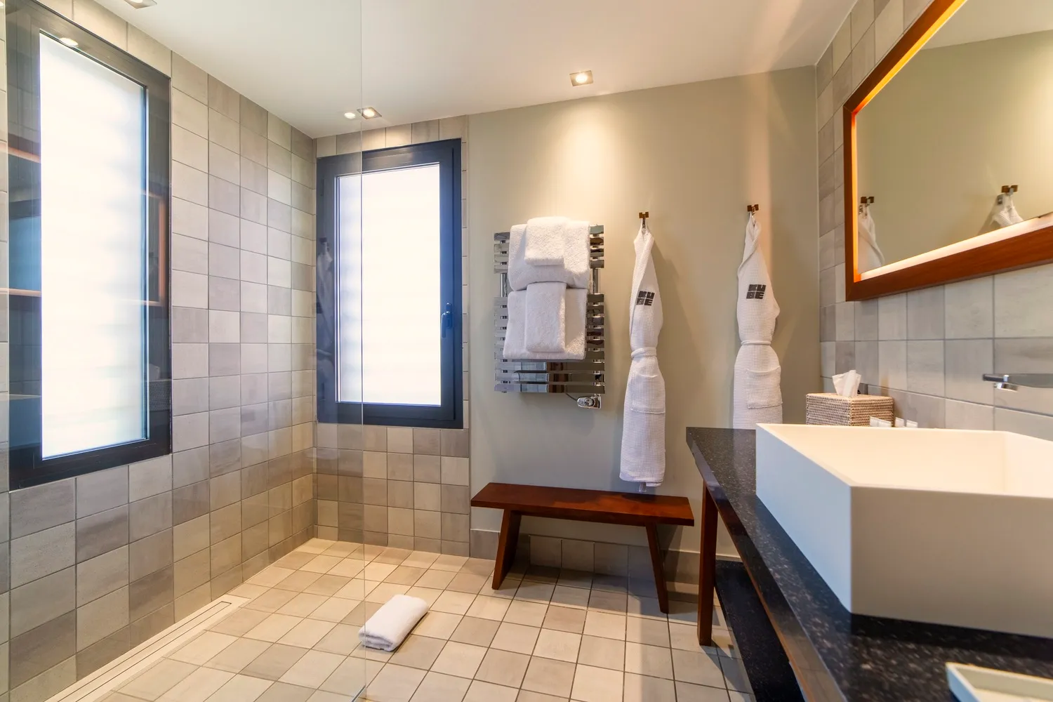 Salle de bain de standing avec vasque rectangulaire, grand miroir design et finitions en matériaux naturels.