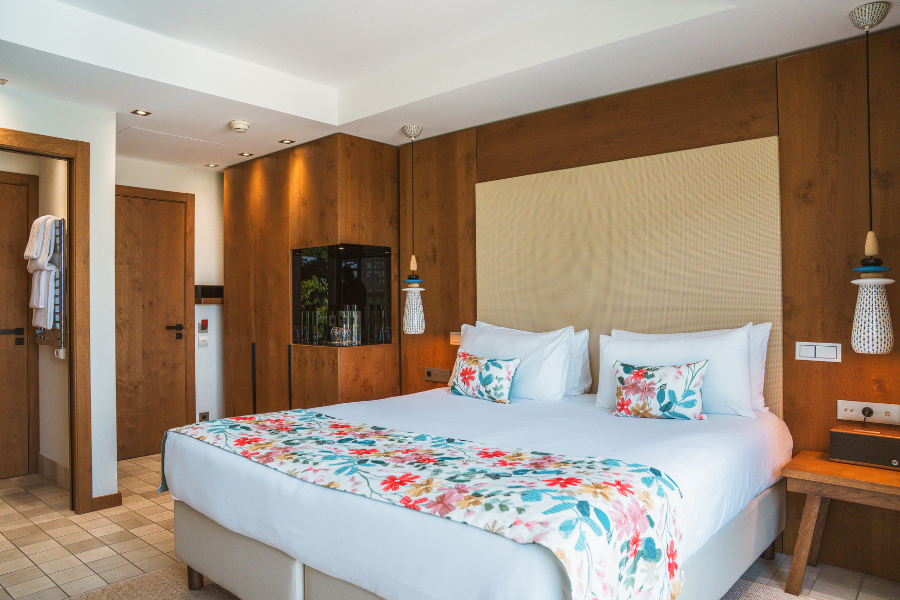 Décoration intérieure d'une suite Wood avec finitions boisées artisanales, table de chevet moderne et parquet massif.