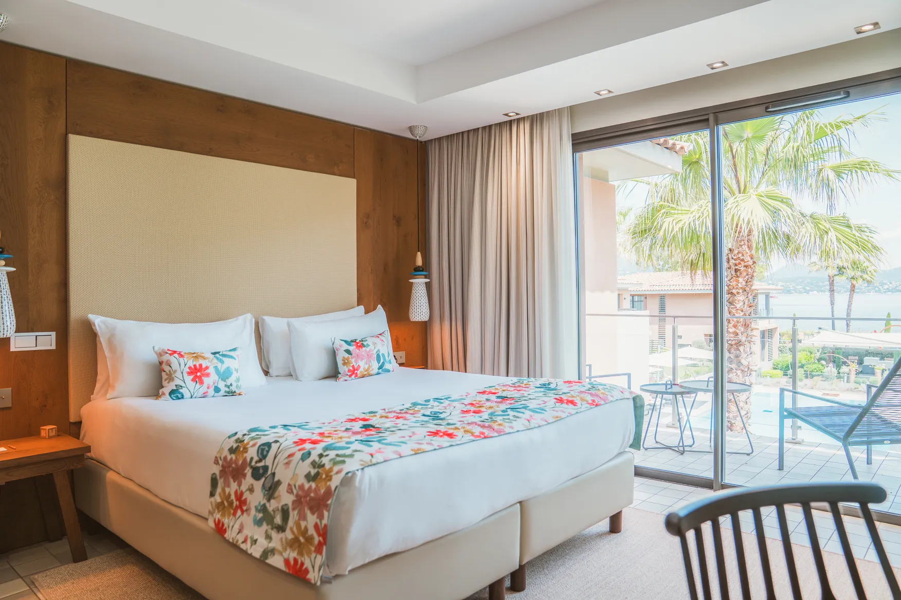 Suite Wood de luxe avec tête de lit monumentale en bois naturel, literie king-size épurée et appliques murales design.