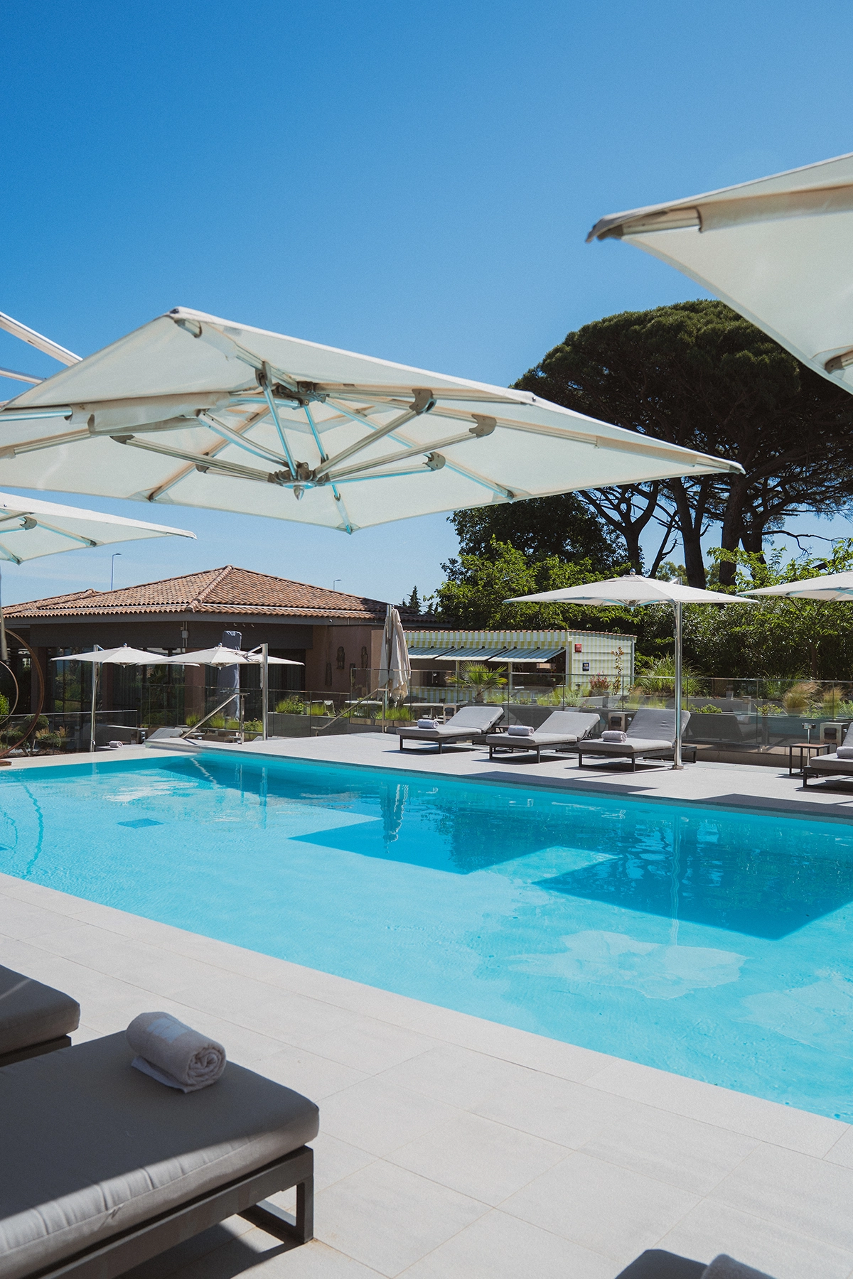 Grande piscine extérieure de luxe entourée de transats et parasols blancs à l'Hôtel Kube Saint-Tropez.