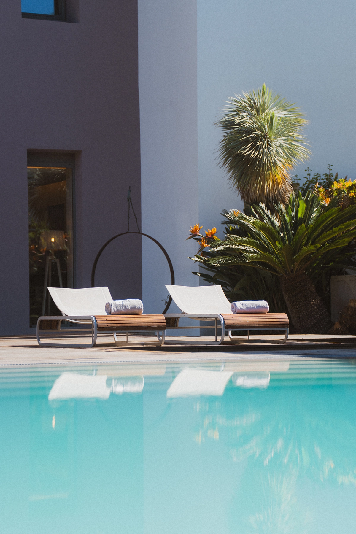 Espace détente avec chaises longues au bord de la piscine de l'Hôtel Kube, cadre moderne et végétation méditerranéenne.