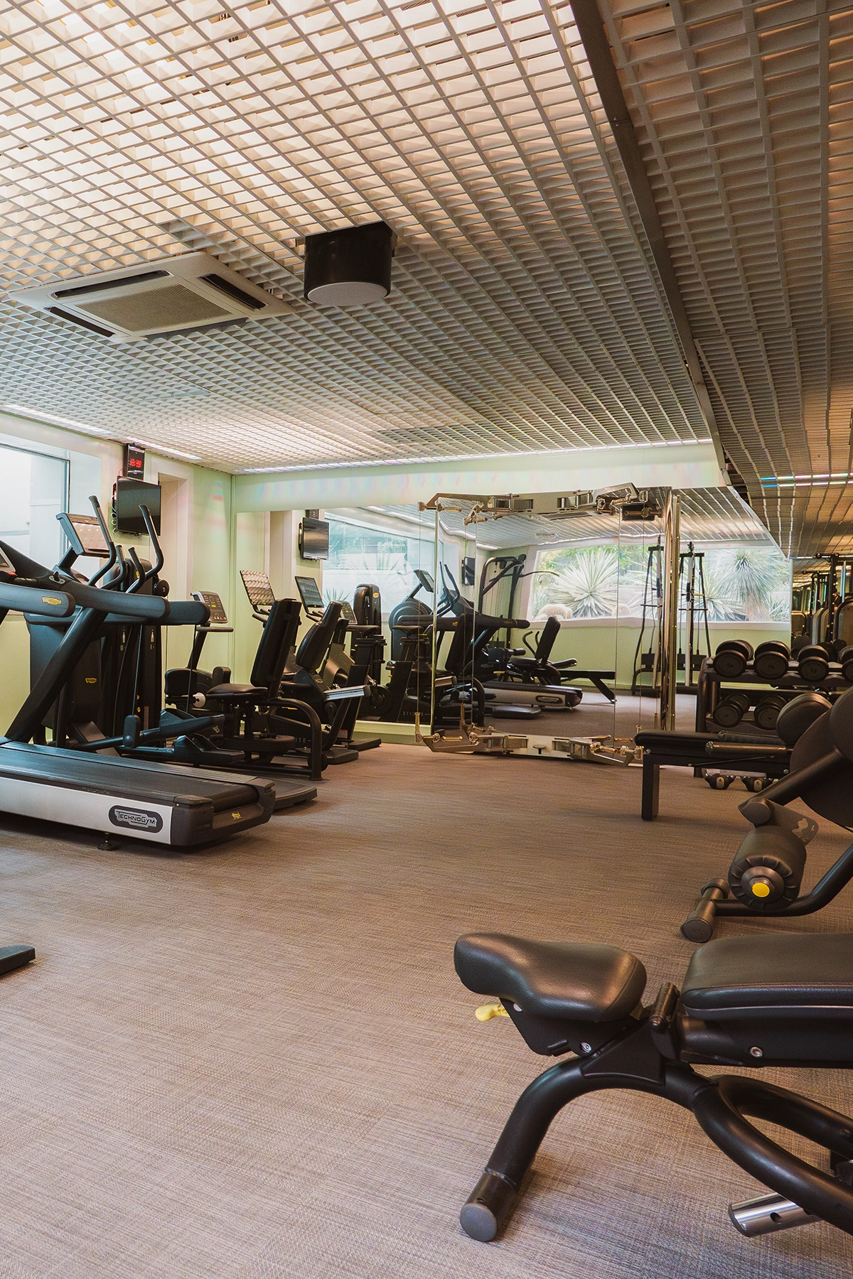 Salle de fitness entièrement équipée avec miroirs et machines de musculation de haute technologie à l'Hôtel Kube.