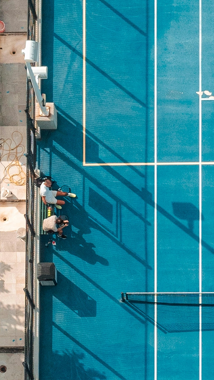 Vue de haut d'un terrain de tennis moderne aux couleurs bleues, situé dans un cadre exclusif à Saint-Tropez.