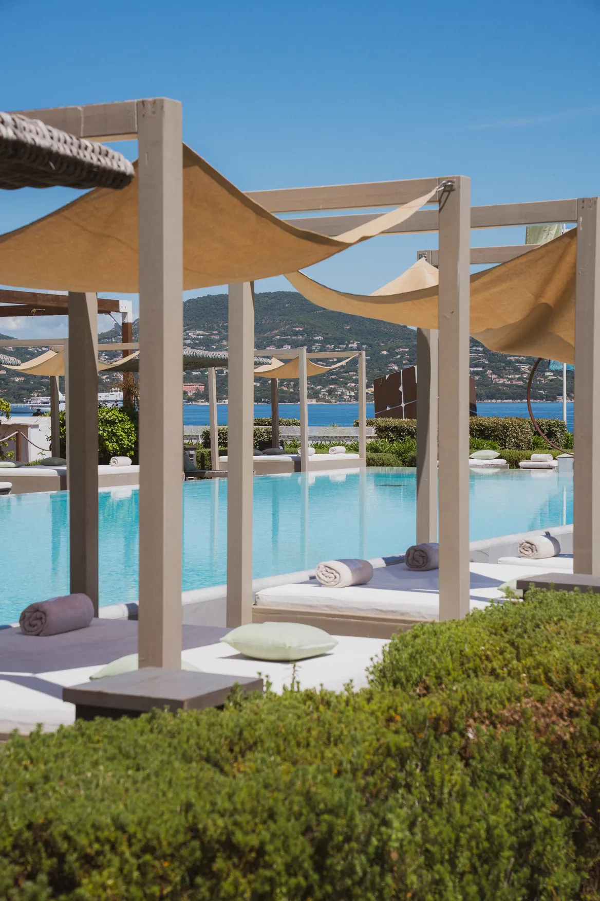 Espace détente extérieur au Kube Hotel : piscine turquoise, voiles d'ombrage et lits balinais face au Golfe.