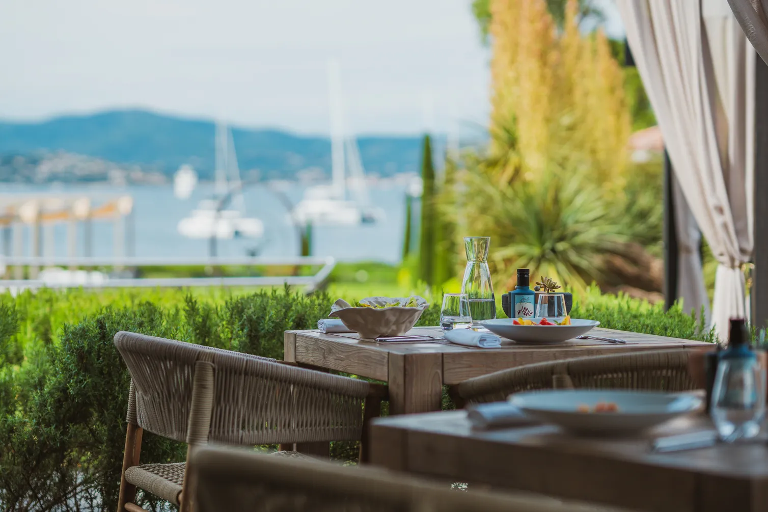 Terrasse de restaurant avec vue mer panoramique sur le Golfe de Saint-Tropez et les yachts, cadre élégant pour un dîner sur la Côte d'Azur.