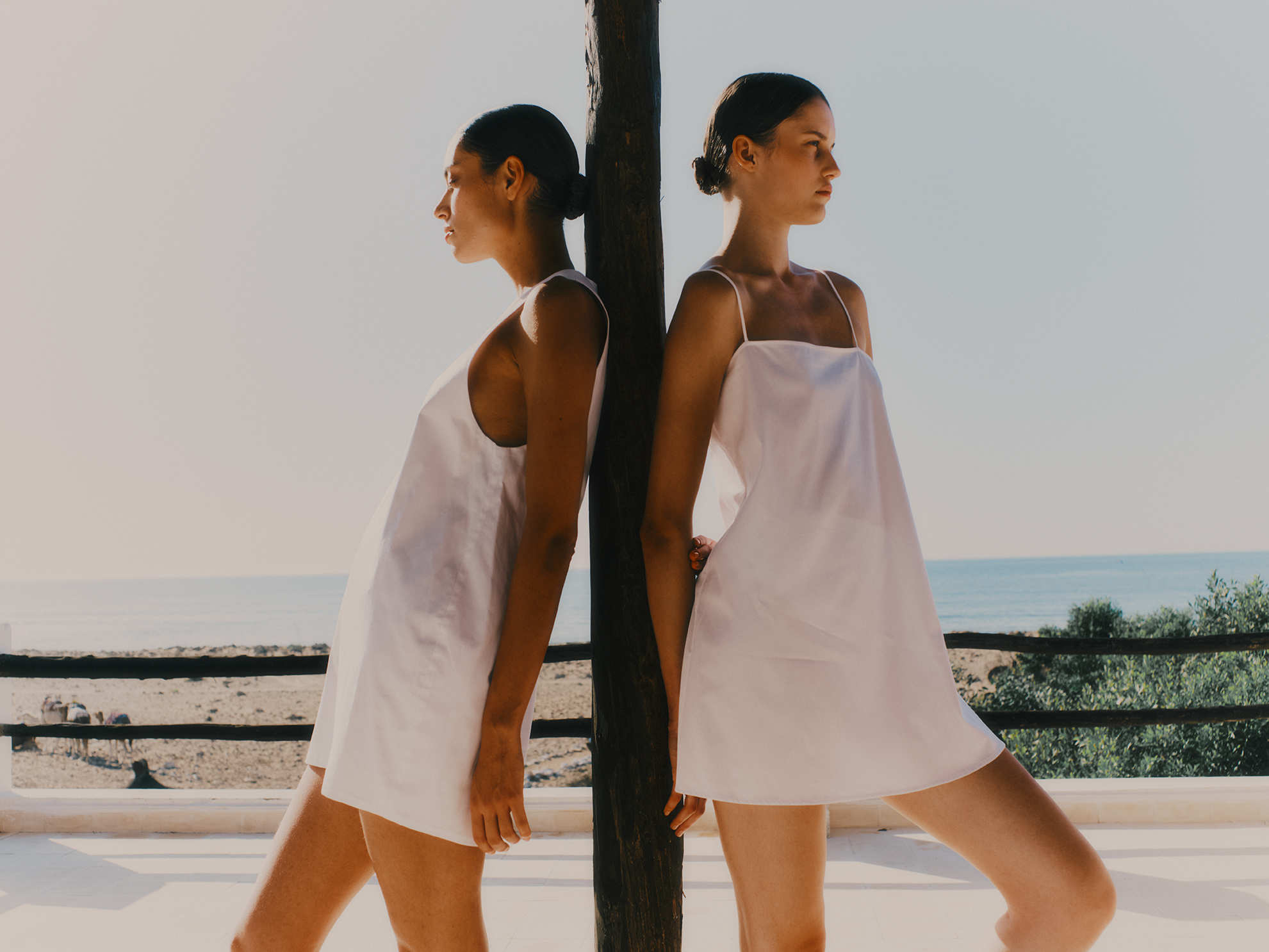 eux femmes de profil portant des robes d'été courtes et légères en lin blanc Vanessa Sposi.