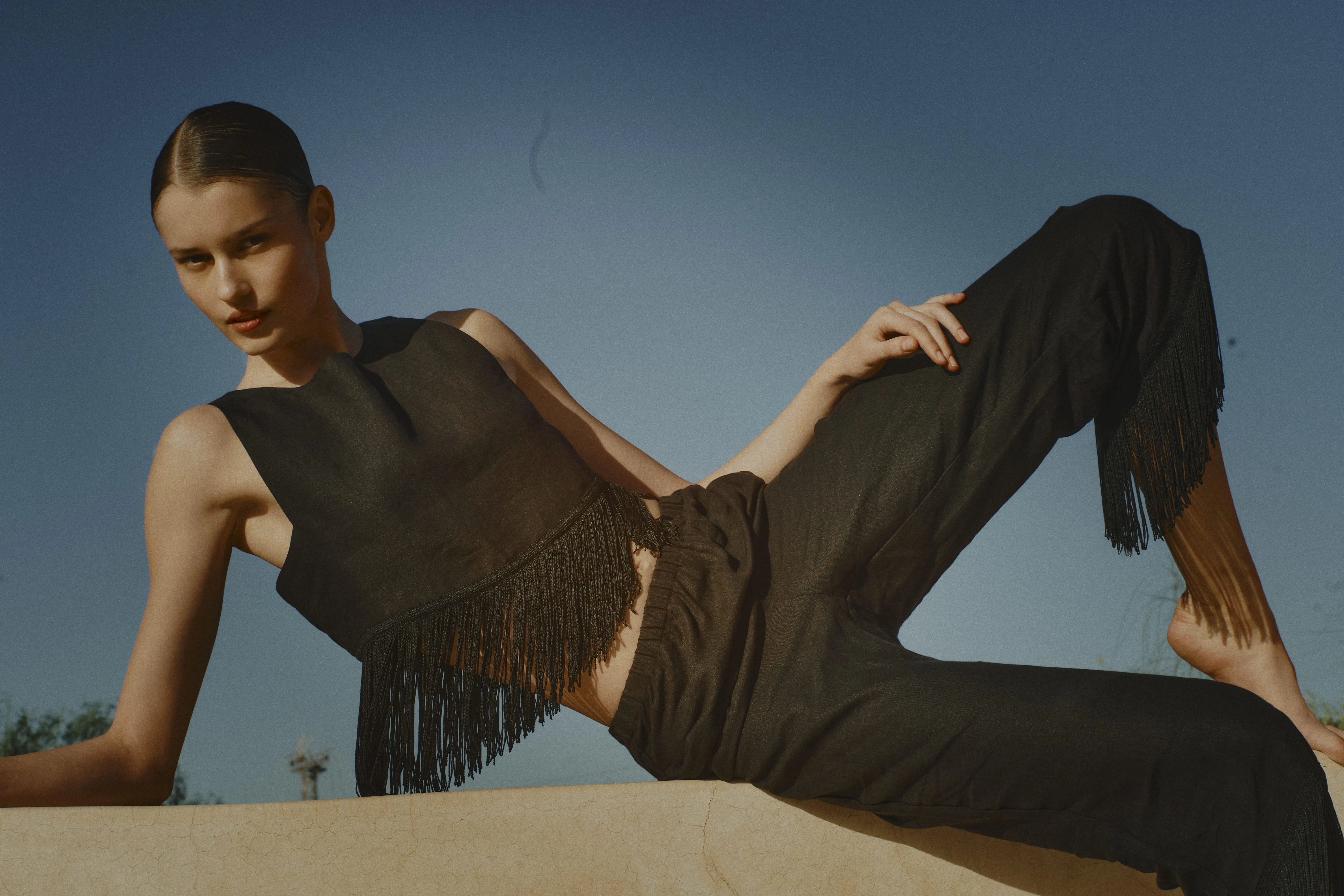 Mannequin portant un ensemble noir avec haut à franges et pantalon fluide de la collection Vanessa Sposi.