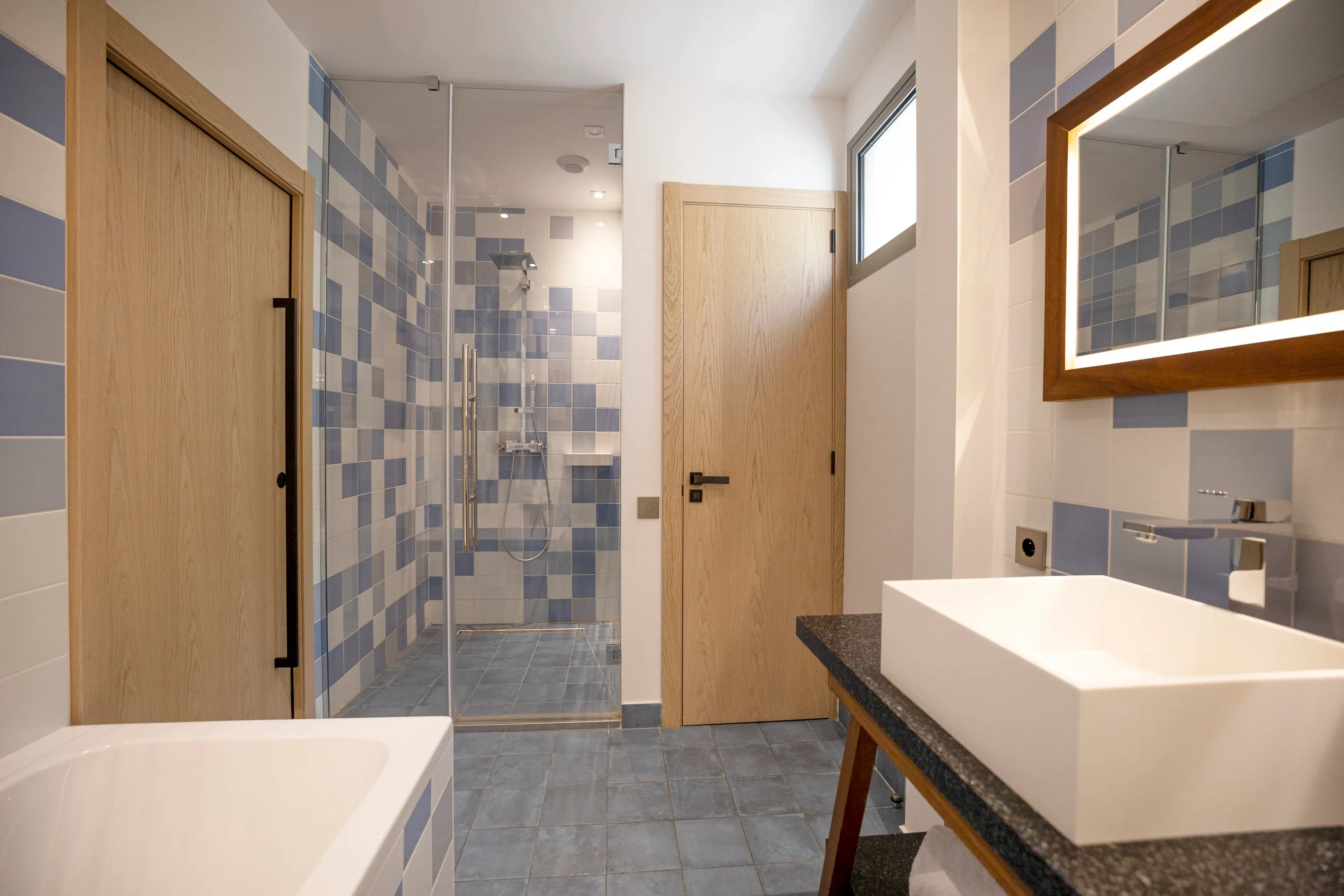 alle de bain de la suite Junior Ibiza équipée d'une douche à l'italienne en mosaïque grise et d'une vasque.