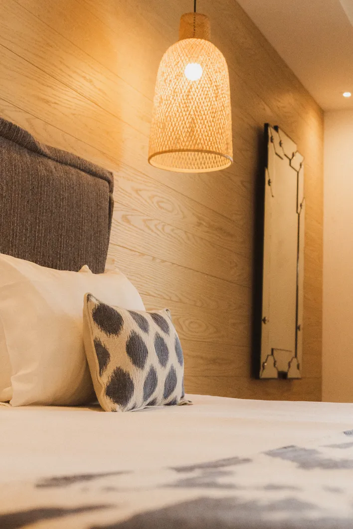 Zoom sur les oreillers à motifs et la suspension lumineuse chaleureuse de la suite Junior Ibiza.