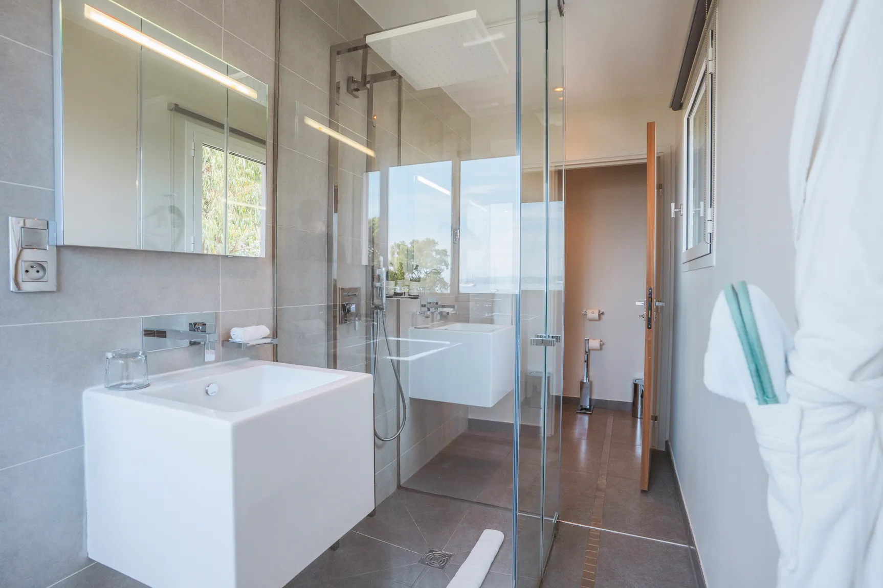 Salle d'eau au design minimaliste avec grand miroir et cabine de douche, suite Natural.