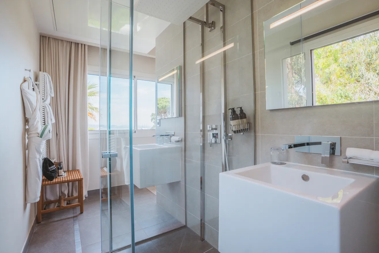 Salle de bain moderne et lumineuse de la chambre Natural avec douche à paroi vitrée et vasque blanche.